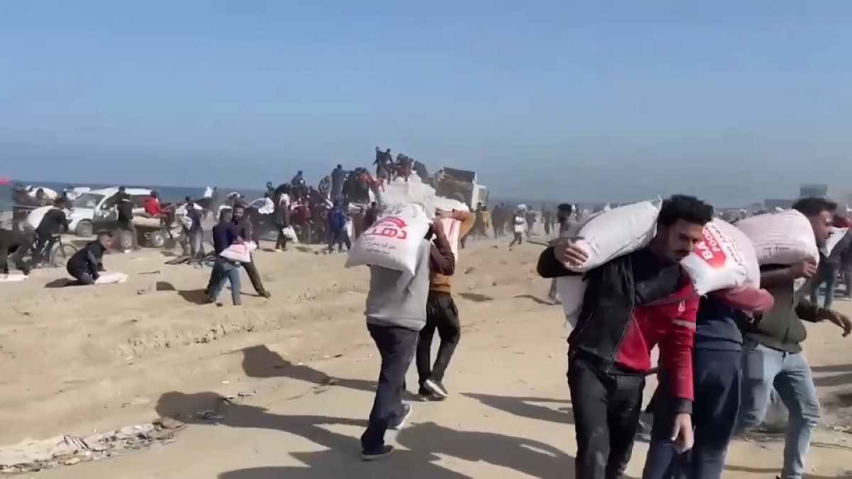 Männer vor Gaza schleppen Mehlsäcke, die ein Hilfstransporter geliefert hat.