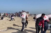 Männer vor Gaza schleppen Mehlsäcke, die ein Hilfstransporter geliefert hat.