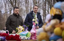 الرئيس الأوكراني زيلينسكي، يسار، ورئيس الوزراء اليوناني كيرياكوس ميتسوتاكيس يضعان الزهور في مكان الهجوم الروسي في منطقة سكنية في 2 مارس، في أوديسا، أوكرانيا، 6 مارس. 2024