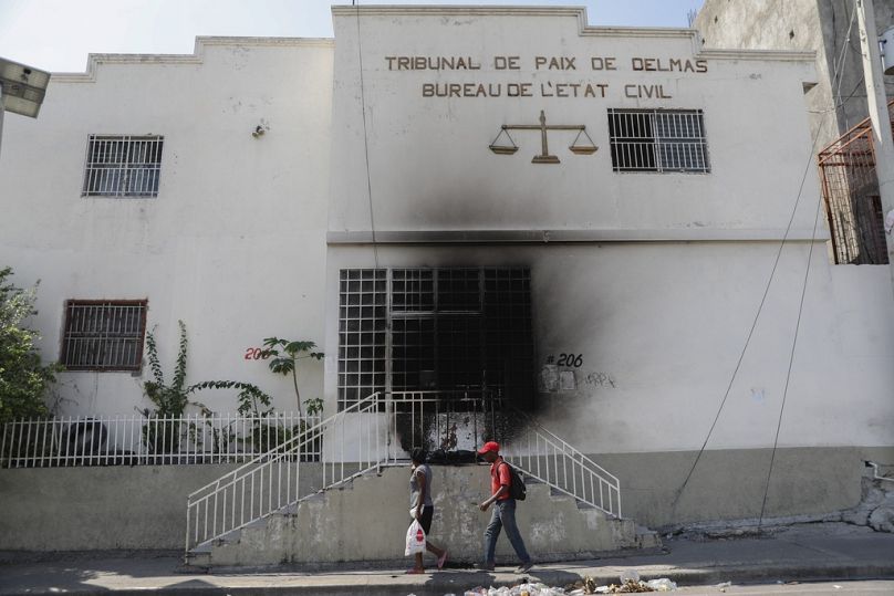 Pedestrians walk past a court building that was set on fire by gangs moments before in the Delmas 28 neighbourhood of Port-au-Prince.
