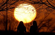 Le persone guardano il tramonto in un parco in una giornata non stagionalmente calda, il 25 febbraio 2024, a Kansas City,