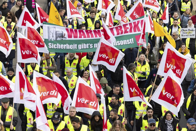 Grevciler Frankfurt'taki protesto sırasında pankartlar ve Ver.di bayraklarıyla Lufthansa Havacılık Merkezi'ne yürüyor