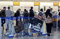 Menschen stehen am Donnerstag, den 7. März 2024, in einem Terminal des Frankfurter Flughafens für Informationen an.