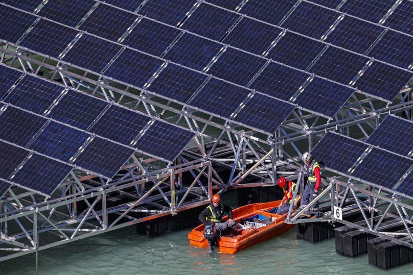 Workers assemble floating barges with solar panels on the 'Lac des Toules', an alpine reservoir lake, in Bourg-Saint-Pierre, October 2018
