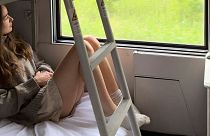 Sarah Marks, of London, looks out at the Italian countryside on TrenItalia's Intercity Notte sleeper train from Palermo to Rome, 10 June 2023.