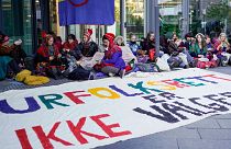 Activists wearing traditional Sami outfits sit in protest outside the entrance of Statkraft, a state-owned company that operates 80 of the wind turbines at Fosen. 