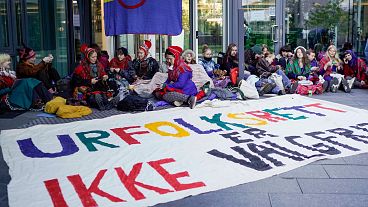 Activists wearing traditional Sami outfits sit in protest outside the entrance of Statkraft, a state-owned company that operates 80 of the wind turbines at Fosen. 