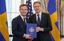 Secretary of State Antony Blinken is seen with Swedish Prime Minister Ulf Kristersson holding Sweden's NATO Instruments of Accession