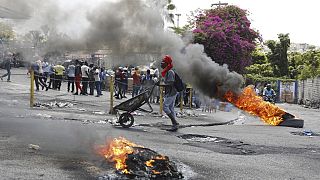 A man pushes a wheelbarrow past burning tires during a protest demanding the resignation of Prime Minister Ariel Henry, in Port-au-Prince, Haiti