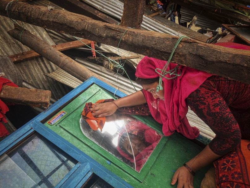 A woman salvages belongings from her home damaged by Cyclone Mocha at Saint Martin island in Cox's Bazar, Bangladesh, May 2023