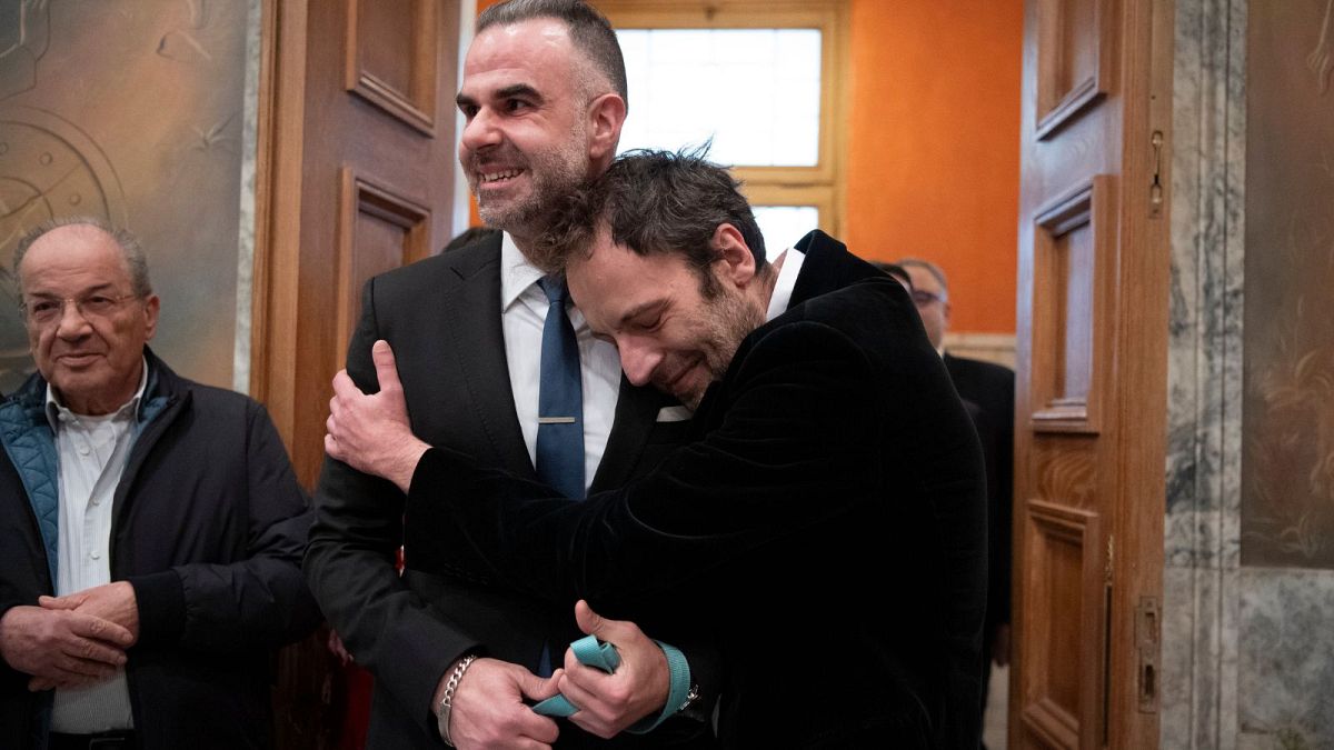Greek author Petros Hadjopoulos, who uses the pen name Auguste Corteau, hugs his husband, lawyer Anastasios Samouilidis, before their wedding at Athens City Hall on Thursday.