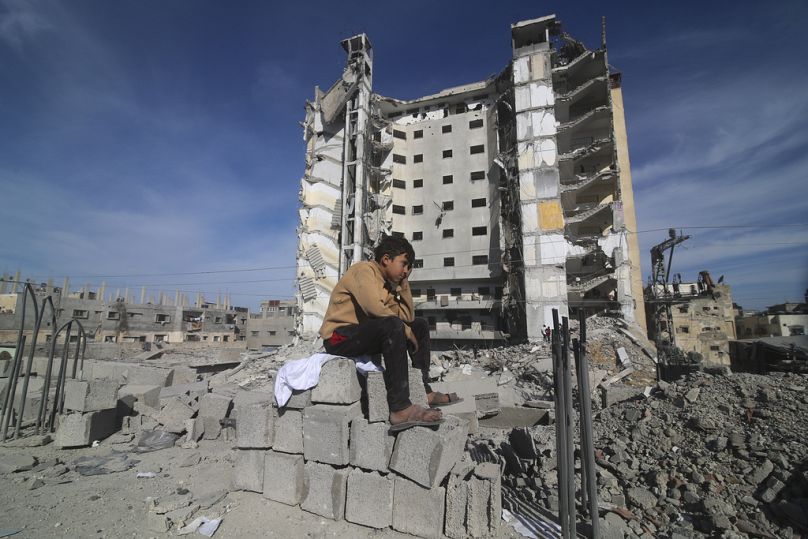 A Palestinian boy sits outside a residential building destroyed in an Israeli strike in Rafah, Gaza Strip, Saturday, March 9, 2024.