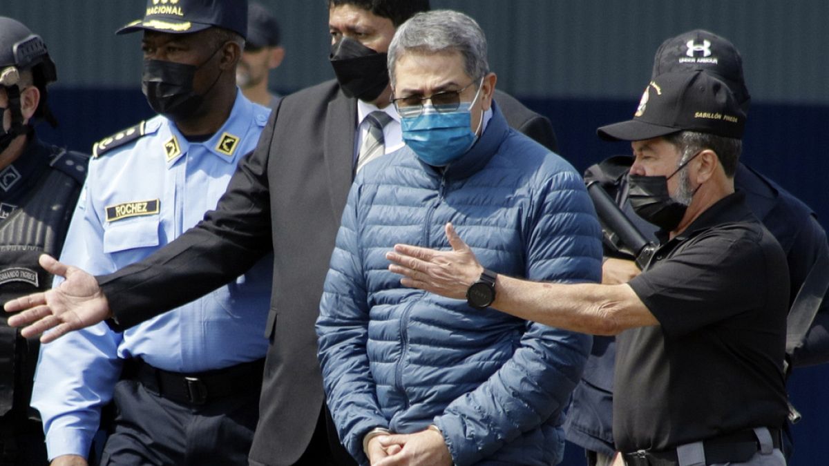 Ο πρώην πρόεδρος της Ονδούρας Χουάν Ορλάντο Ερνάντες, δεύτερος από δεξιά, περνάει χειροπέδες κατά την έκδοσή του στις Ηνωμένες Πολιτείες, 21 Απριλίου 2022.