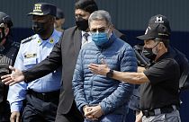 O antigo presidente hondurenho Juan Orlando Hernandez, segundo a contar da direita, é algemado enquanto é extraditado para os Estados Unidos, 21 de abril de 2022