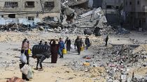 فلسطينيون يسيرون وسط الدمار الذي خلفه الهجوم الإسرائيلي على خان يونس، قطاع غزة، الجمعة، 8 مارس، 2024.