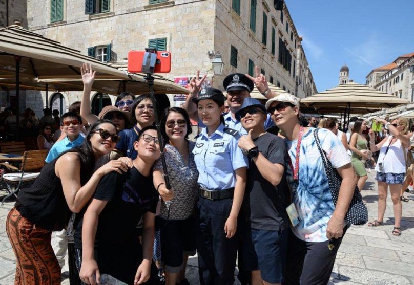Kínai rendőrnővel és horvát rendőrrel szelfiznek a turisták, 2019 augusztusában