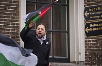 Un hombre ondea una bandera palestina mientras protesta contra la asistencia del presidente israelí a la inauguración del nuevo Museo del Holocausto en Ámsterdam.