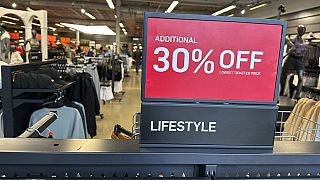 A sign trumpets the discounts available on items in a sports apparel store in the Thornton Premium Outlets Monday, Dec. 18, 2023, in Thornton, Colo. 