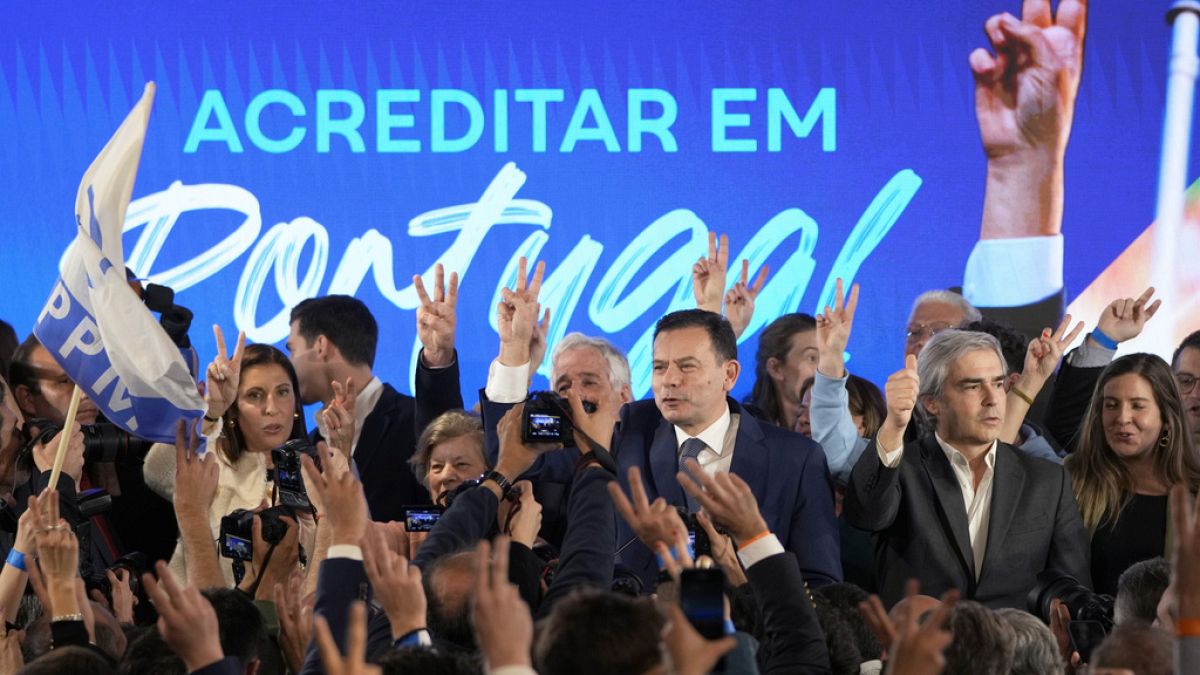 Luis Montenegro, leader of the center-right Democratic Alliance, center, and his wife Carla, at left, gesture to supporters after claiming victory in Portugal's election, in L