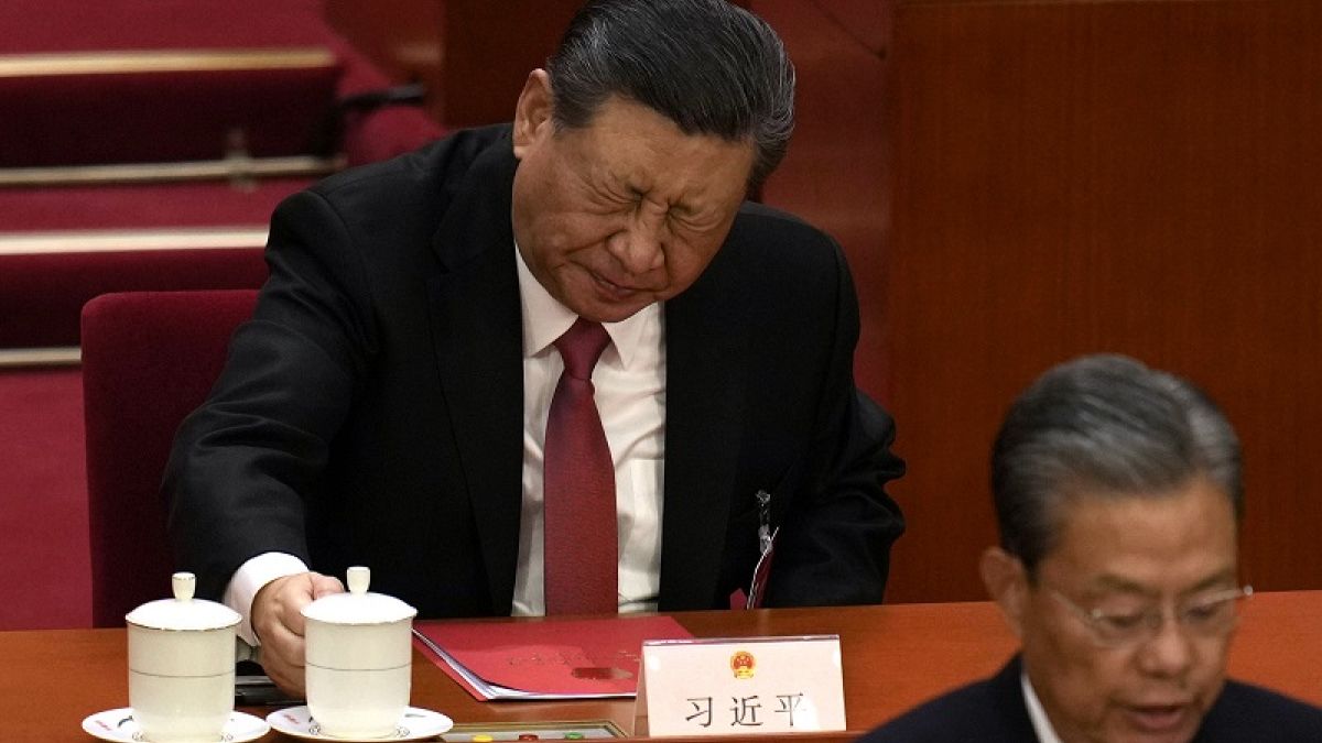 Hszi Csin-ping kínai elnök (hátul) reagál, miután ivott egy pohárból az Országos Népi Kongresszus záróülésén a Nép Nagy Csarnokában Pekingben, 2024. március 11-én