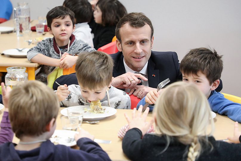 French President Emmanuel Macron meets pupils as he visits a school canteen in Saint-Sozy, southwestern France