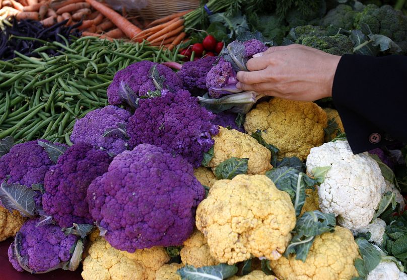 A shopper chooses from a variety of cauliflower