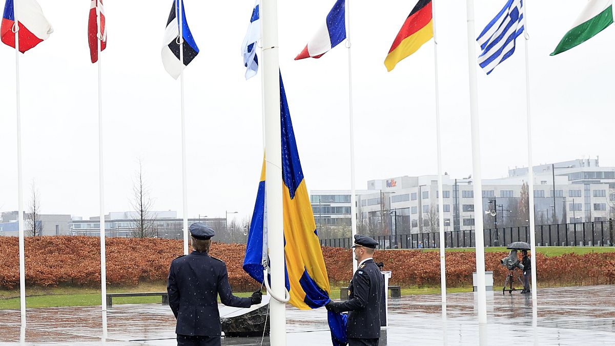 Dos militares se preparan para izar la bandera de Suecia durante una ceremonia en Bruselas este lunes 11 de marzo de 2024