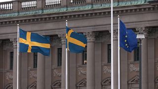 Bandeiras da Suécia e da União Europeia em frente ao Parlamento sueco em Estocolmo.