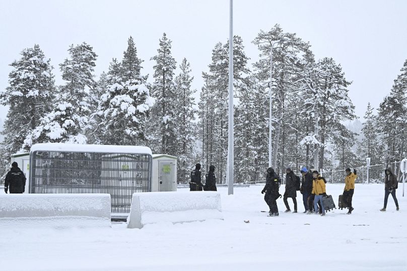 Finn határőrök menedékkérőket kísérnek a finn-orosz határon