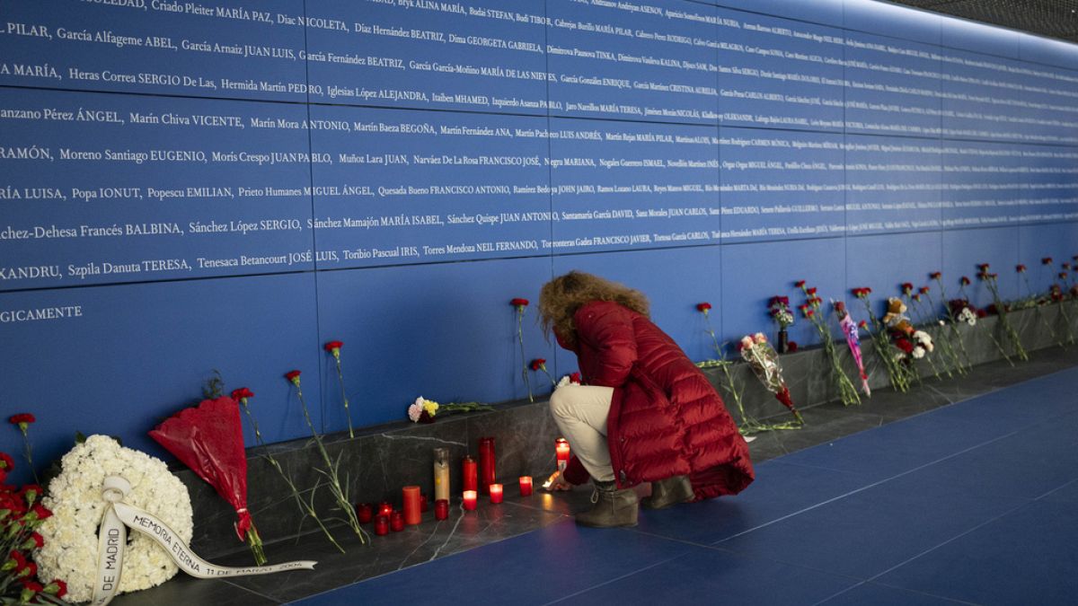 Una mujer enciende una vela en un monumento a las víctimas del atentado en el tren dentro de la estación de tren de Atocha en Madrid, España, el lunes 11 de marzo de 2024.