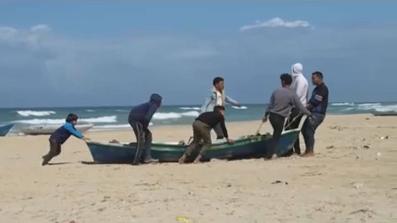 فلسطينيون يسحبون أحد القوارب على ساحل غزة
