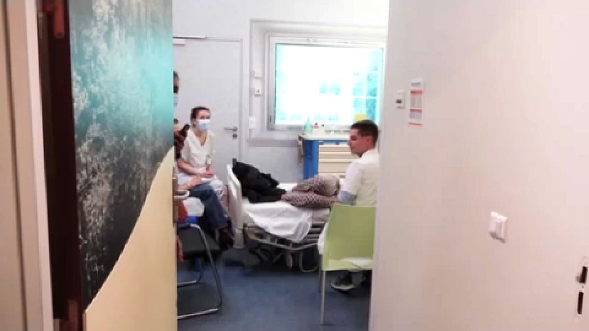 Imagen de una habitación de un hospital en la que aparecen varios trabajadores sanitarios en torno a la cama en la que descansa un paciente. 