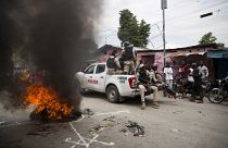 ضباط الشرطة الوطنية يمرون بإطارات مشتعلة خلال مظاهرة تطالب باستقالة رئيس هايتي