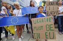Protestors hold signs and EU and Ukrainian flags during a demonstration in support of Ukraine outside of an EU summit in Brussels, on June 23, 2022.