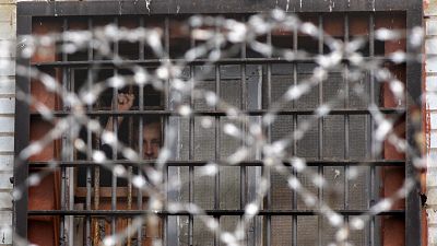 Detenido bielorruso hace gestos desde una celda de un centro de detención en Minsk, Bielorrusia, el 7 de julio de 2011.