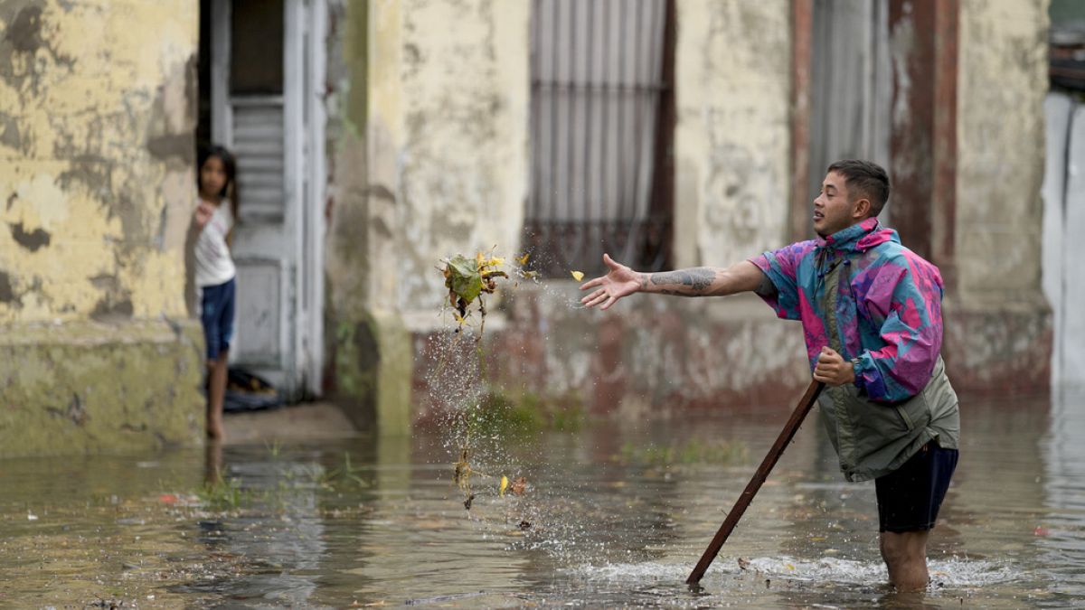 Un residente cerca di sturare un tombino in una strada allagata dopo una forte pioggia ad Avellaneda, alla periferia di Buenos Aires, Argentina, 12 marzo 2024