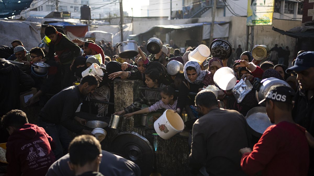 Palestinianos fazem fila para terem acesso a uma refeição gratuita em Rafah, na Faixa de Gaza.