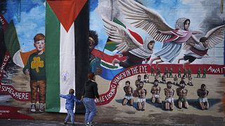 امرأة وطفل يسيران خلال إزاحة الستار عن الجدار الدولي بعد تحويله إلى لوحة جدارية في غزة