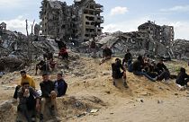 مجموعة من الشباب يجلسون وسط الأنقاض والردم في قطاع غزة 