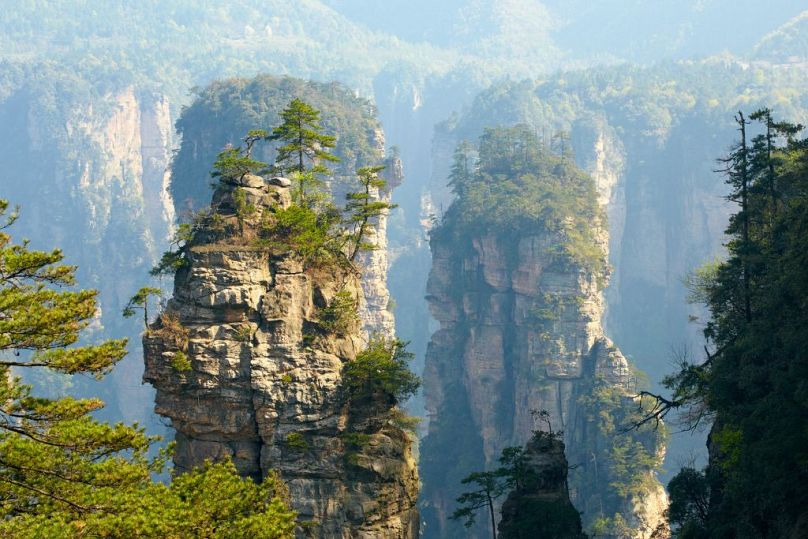 Explore the otherworldly landscapes of Zhangjiajie National Forest Park, where towering sandstone pillars inspired the floating mountains of James Cameron's Avatar.