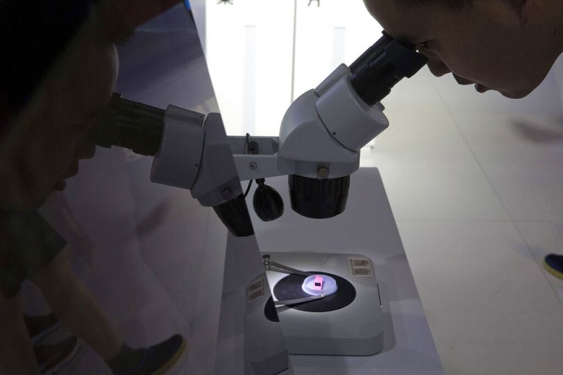 A visitor to the 21st China Beijing International High-tech Expo looks at a computer chip through the microscope, in Beijing, May 2018