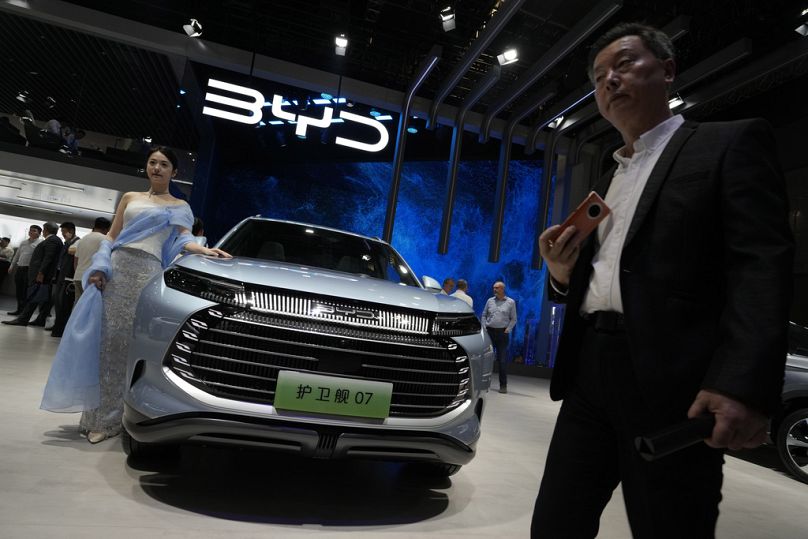 A model stands next to a car from BYD during the Shanghai auto show in Shanghai, April 2023