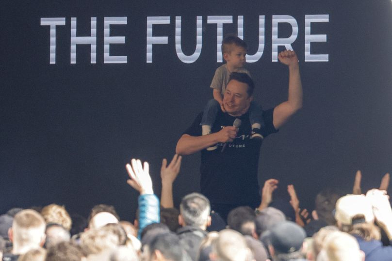 Tesla CEO Elon Musk enters the stage with a child on his shoulders at the Tesla Gigafactory for electric cars in Gruenheide near Berlin, March 2024