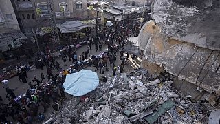 Palestinians shop at a local market next to a destroyed residential building by the Israeli airstrikes, during the Muslim holy month of Ramadan, in Rafah, Gaza Strip, Thursday
