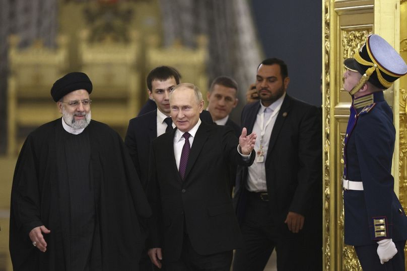 Russian President Vladimir Putin, center, welcomes Iranian President Ebrahim Raisi, left, for the talks at the Kremlin in Moscow, Russia