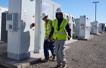 Workers walks the campus of battery storage pods at Orsted's Eleven Mile Solar Center lithium-ion battery storage energy facility Thursday, Feb. 29, 2024, in Coolidge, Ariz. 