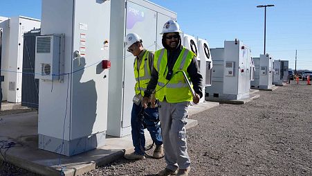 Workers walks the campus of battery storage pods at Orsted's Eleven Mile Solar Center lithium-ion battery storage energy facility Thursday, Feb. 29, 2024, in Coolidge, Ariz. 