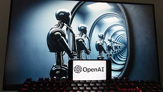 Le logo d'OpenAI sur un téléphone portable, devant une image générée par le modèle texte-image Dall-E de ChatGPT affichée sur un écran d'ordinateur.