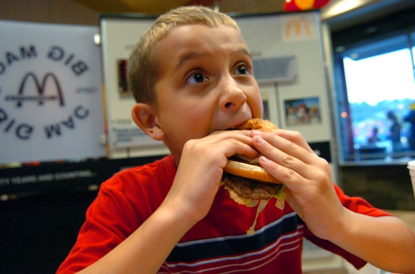 A child bites into a Big Mac during the opening of a McDonald's Big Mac Museum Restaurant in North Huntingdon, PA, August 2007