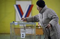 Un'elettrice mette la scheda nell'urna in un seggio di San Pietroburgo